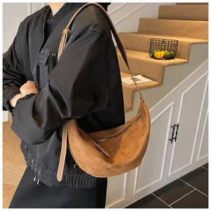 Brown faux suede crescent bag showing matte texture and adjustable strap in lifestyle setting