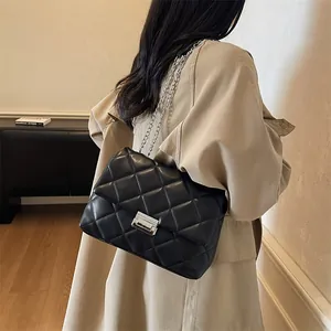 Quilted leather shoulder bag with silver chain and metal lock on trench coat