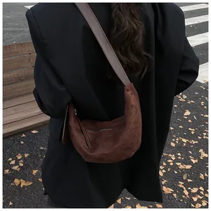 Close-up of brown suede hobo bag styled with a black blazer on a street bench