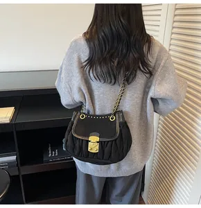 Détail du sac bandoulière plissé noir avec chaîne dorée et fermoir métallique