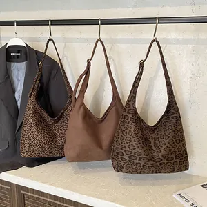 Three vintage leopard print and suede tote bags hanging on a minimalist display