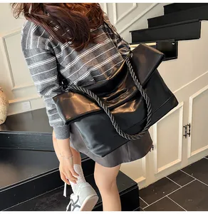 Detailed view of the large black tote bag featuring a chunky braided top handle and matte texture