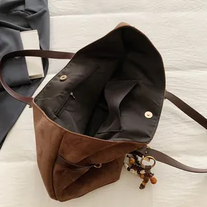 Brown suede tote bag with spacious interior and vintage wooden bead pendant detail