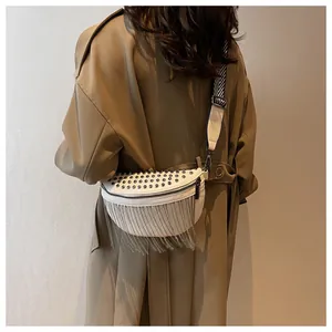 Close-up of white crossbody bag with silver rivets, metal fringe and wide patterned strap