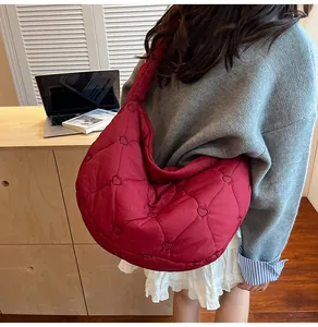 Bolso acolchado rojo con bordado de corazones lucido por una modelo en un ambiente interior