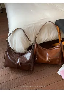 Detail of glossy wrinkled leather tote bags in dark coffee and caramel colors with gold zips