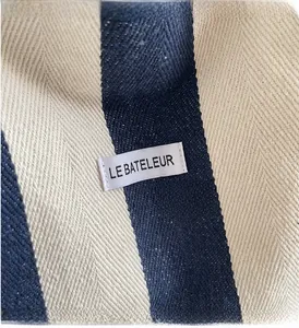 Close-up of blue striped canvas fabric with Le Bateleur woven label and twill texture