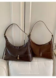 Close-up of retro dark brown hobo bags with glossy leather texture and gold hardware details
