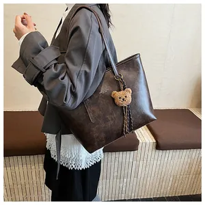 Dettaglio di una borsa tote vintage in pelle marrone con un simpatico orsetto di peluche