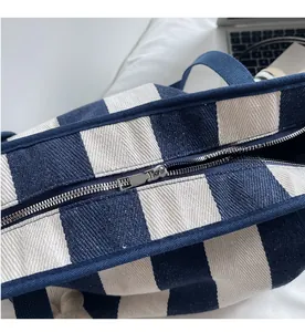 Detail of smooth metal zipper closure on striped canvas tote bag with durable stitching