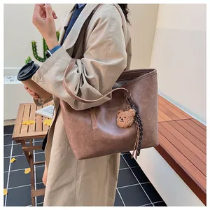 Dettaglio della grande borsa tote vintage marrone scuro con ciondolo a orso e texture