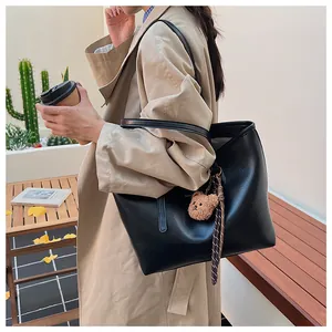 Dettaglio di una grande borsa tote in pelle PU nera con un ciondolo a forma di orsetto