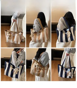 Detail of striped canvas tote bag with brand label and plush puppy keychain accessory