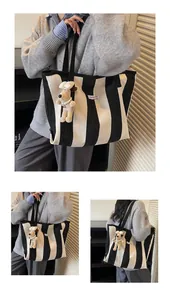 Macro detail of large black and white striped tote bag with plush dog charm and logo