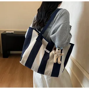 Detail of striped canvas tote bag with navy blue straps and a cute puppy plush charm
