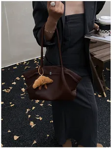 Detail of dark brown pebble leather tote bag with a cute croissant plush charm attachment