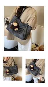 Close-up of grey tote bag with embossed letters and cute bear charm detail