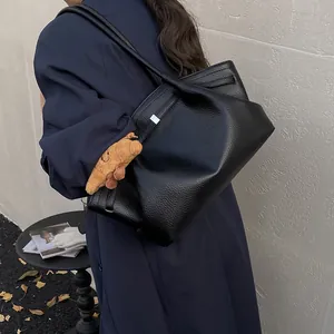 Classic black leather tote bag with pebble texture and star charm shown on shoulder