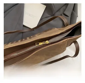 Close-up of golden metal zipper detail on brown textured tote bag with fabric lining