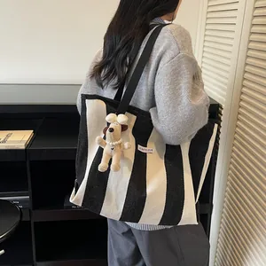 Minimalist black and white striped canvas tote bag with a cute dog plush charm and wide strap