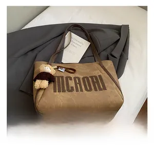 Detail of vintage brown tote bag with 3D MCAORI embroidery and cute teddy bear pendant