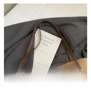 Close-up of canvas tote bag with brown leather handles and a cute plush bear charm