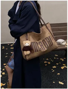 Detailed close-up of brown tote bag with MCA ORI lettering and a cute bear keychain