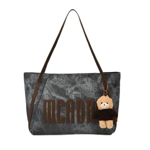 Dark gray textured tote bag with brown leather handles and a plush bear pendant