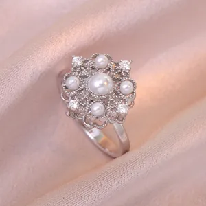 Collier élégant à fleur rotative avec zircon et perles sur fond de satin champagne