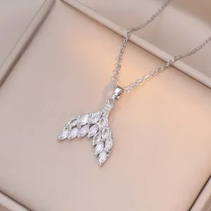 Macro shot of silver fishtail pendant with marquise zircons on champagne silk