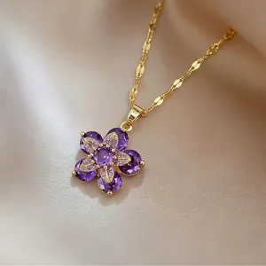 Elegant gold necklace with purple pear-cut gemstone flower pendant on cream fabric
