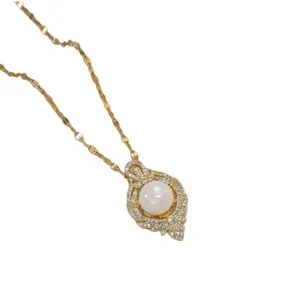 Close-up of a gold pearl necklace with a shimmering white pearl and diamond-encrusted bezel