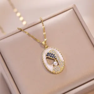 Exotic gold oval necklace featuring white enamel, blue zircon, and a pearl accent