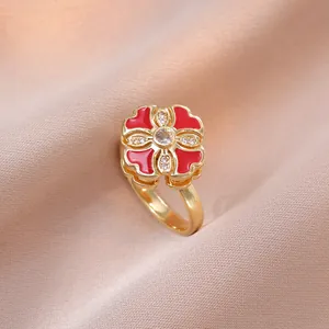 Bague trèfle rotative dorée avec émail rouge et zircons brillants sur soie rose