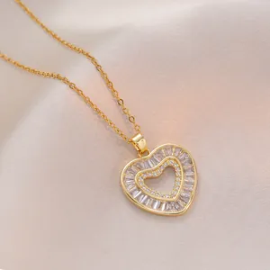 Golden heart pendant necklace with baguette cubic zirconia on pink fabric background