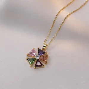 Collier en titane doré avec pendentif fleur orné de zircons colorés sur de la soie blanche