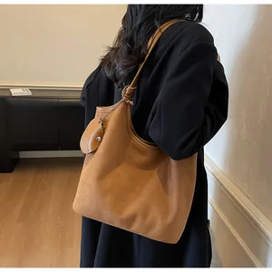 Dettaglio della borsa tote in pelle scamosciata caramello con tracolla annodata e ciondolo a cuore