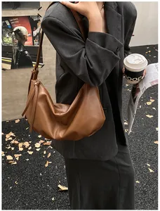Detailed view of brown PU leather crescent bag with stylish tassel and pleats