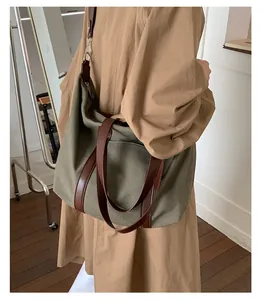 Detail of olive green canvas tote bag with brown leather straps worn on shoulder