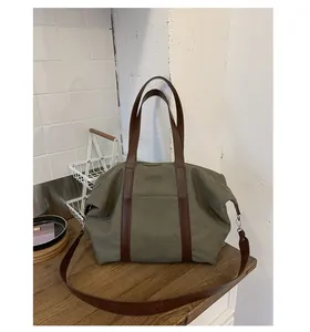 Detail view of olive green canvas tote bag with brown leather handles and front pocket