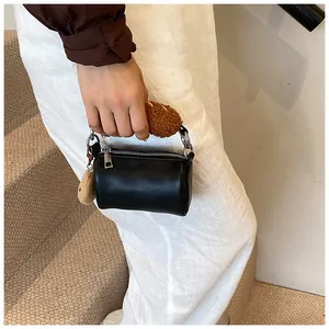 Détail d'un sac cylindrique noir avec poignée en peluche marron et breloque décorative