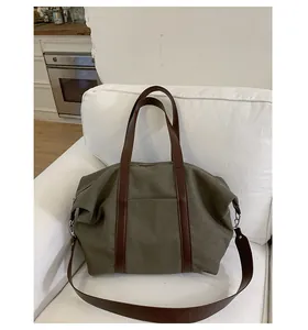 Detail view of large canvas tote bag with brown leather straps on a white sofa