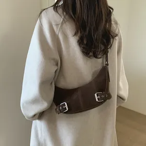Retro dark brown crescent shoulder bag with metallic buckle detail on white coat model