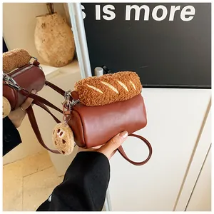 Détail d'un sac bandoulière cylindrique marron avec breloque baguette et biscuit
