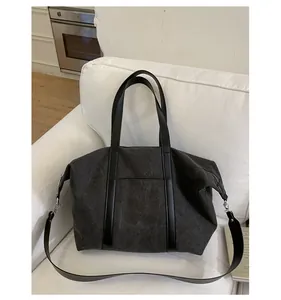 Detail view of canvas tote bag with leather straps and silver buckle on white sofa