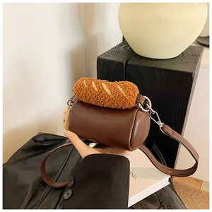 Détail d'un sac bandoulière cylindrique marron avec un charmant pain baguette en peluche