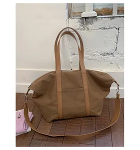 Close-up of a large canvas tote bag with adjustable shoulder strap and top zipper closure