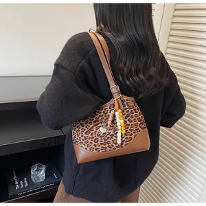 Detail of leopard print shoulder bag with leather bow and heart pendant on model