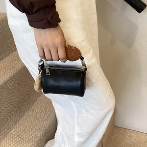 Mini sac cylindrique en cuir noir avec poignée en peluche et joli pendentif crème