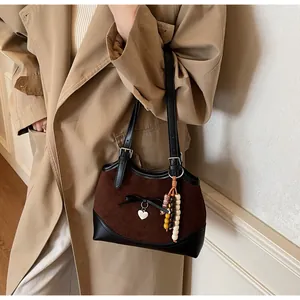 Detail of leopard print tote featuring brown suede, black leather handles and heart charm